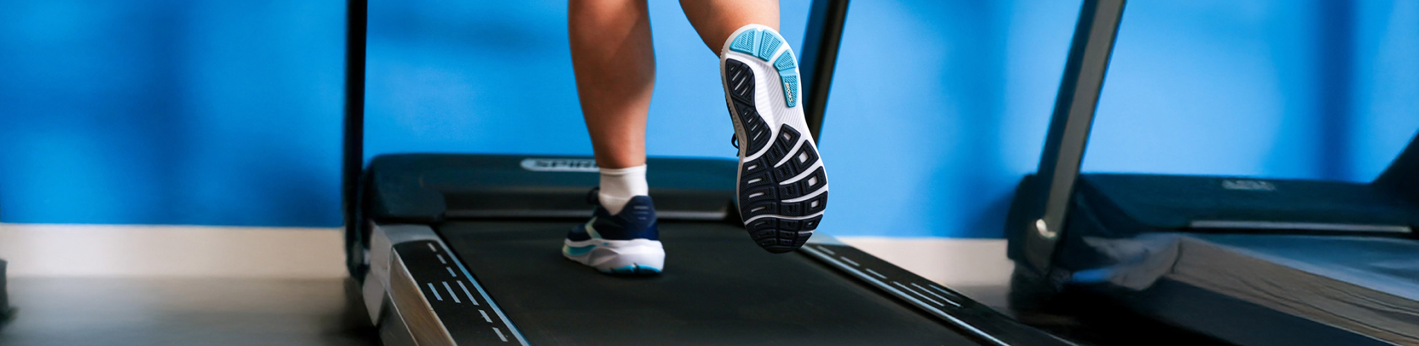 Lower legs wearing trainers running on a running machine